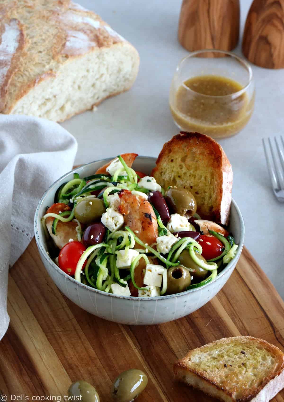 L'été s'invite dans notre assiette avec cette salade grecque de poulet aux spaghettis de courgettes et à la feta. Réalisée avec des courgettes coupées sous forme de spaghettis (zoodles), cette salade tiède est savoureuse, équilibrée, et réalisée sans gluten. 