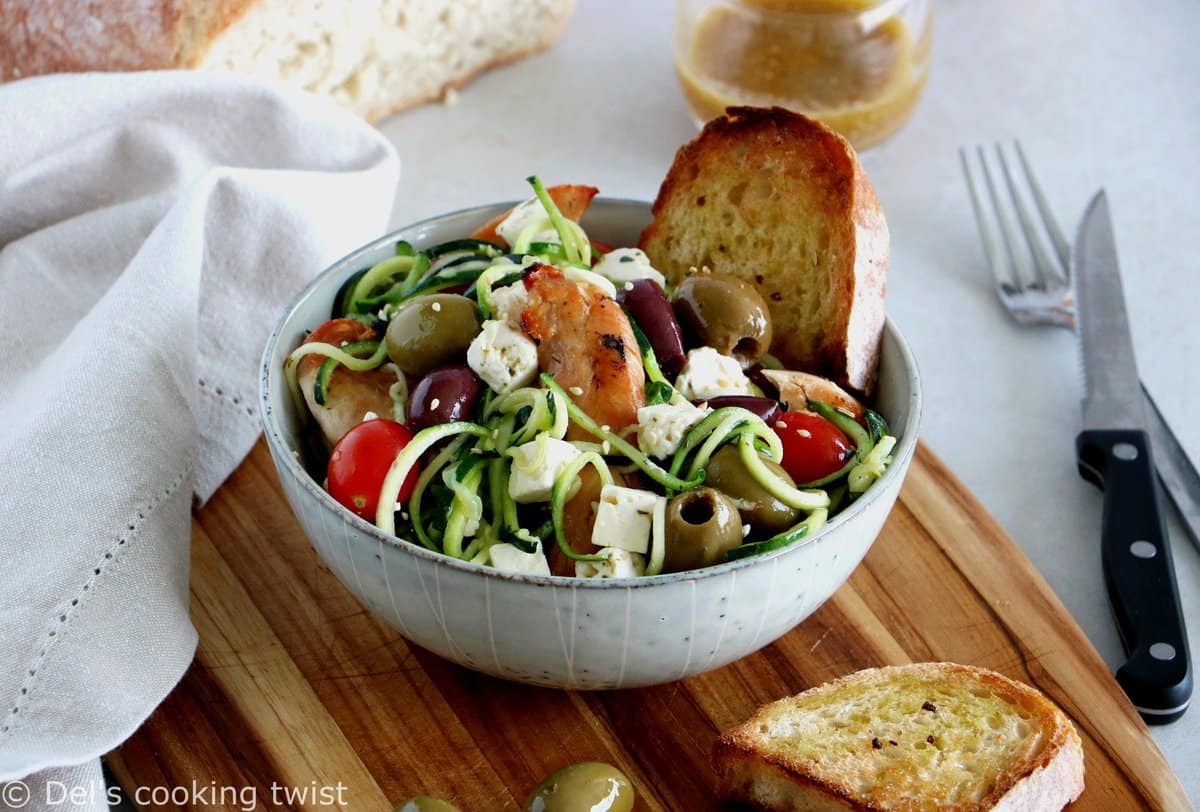 L'été s'invite dans notre assiette avec cette salade grecque de poulet aux spaghettis de courgettes et à la feta. Réalisée avec des courgettes coupées sous forme de spaghettis (zoodles), cette salade tiède est savoureuse, équilibrée, et réalisée sans gluten. 