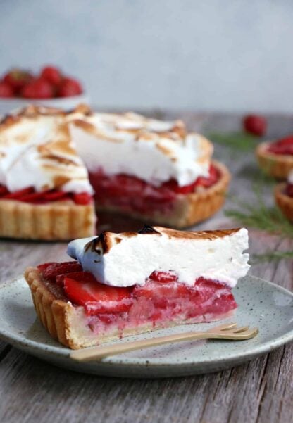 Tarte meringuée aux fraises et à la rhubarbe. De la gourmandise à l'état pur pour cette tarte meringuée aux fraises et à la rhubarbe aux saveurs acidulées. On y retrouve une crème d'amande, des fruits juteux et une onctueuse meringue italienne.