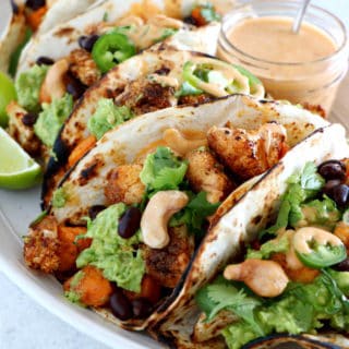 Spicy Vegan Sweet Potato and Cauliflower Tacos. Healthy vegan tacos filled with roasted sweet potato and cauliflower, mashed avocado and topped with a spicy cashew sauce. They are loaded with healthy and hearty flavors and make a perfect, quick, and easy weeknight dinner. These tacos are Oh SO good!