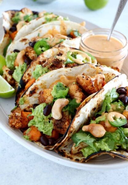 Spicy Vegan Sweet Potato and Cauliflower Tacos. Healthy vegan tacos filled with roasted sweet potato and cauliflower, mashed avocado and topped with a spicy cashew sauce. They are loaded with healthy and hearty flavors and make a perfect, quick, and easy weeknight dinner. These tacos are Oh SO good!