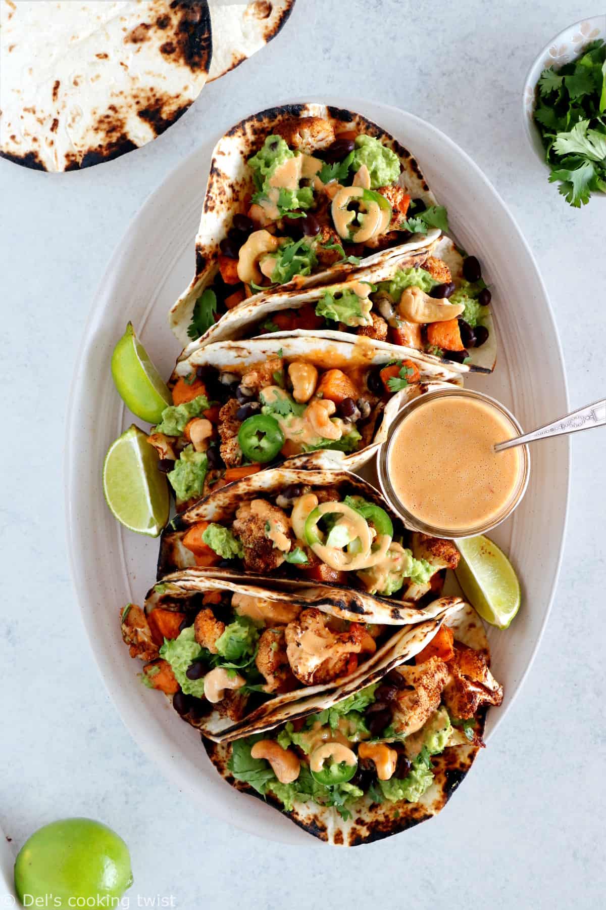 Tacos vegan garnis de patates douces et fleurets de chou-fleur rôtis, le tout réhaussé d'une sauce épicée aux noix de cajou et harissa. Ces tacos sont parfaits pour un dîner rapide entre amis, à la fois sain, nourrissant et très gourmand.