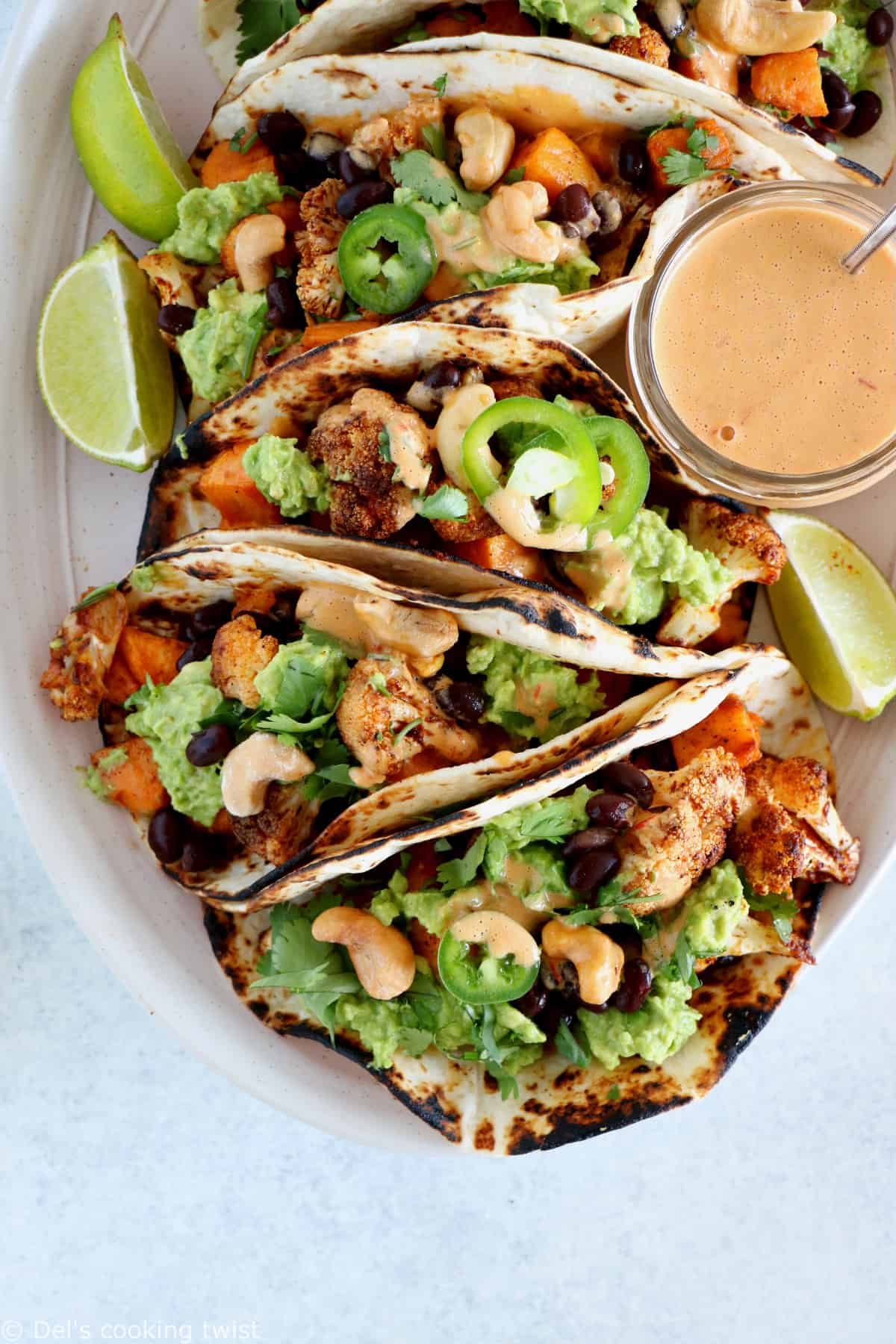 Tacos vegan garnis de patates douces et fleurets de chou-fleur rôtis, le tout réhaussé d'une sauce épicée aux noix de cajou et harissa. Ces tacos sont parfaits pour un dîner rapide entre amis, à la fois sain, nourrissant et très gourmand.