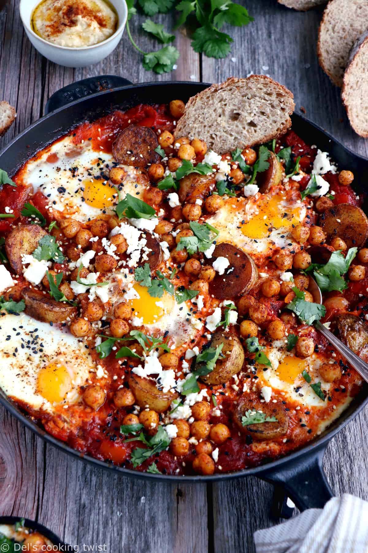 Une shakshuka en version deluxe, avec une base d'oeufs pochés plongés dans une sauce tomate aux oignons, le tout réhaussé de pommes de terres et pois chiches épicés.