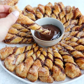 Vous ne résisterez pas à cette tarte soleil façon churros. Déchirez les torsades de pâte feuilletée recouvertes d'un mélange sucre-cannelle, trempez-les dans la sauce au chocolat chaud et dévorez sans plus attendre.