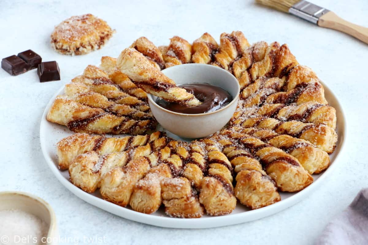 Vous ne résisterez pas à cette tarte soleil façon churros. Déchirez les torsades de pâte feuilletée recouvertes d'un mélange sucre-cannelle, trempez-les dans la sauce au chocolat chaud et dévorez sans plus attendre.