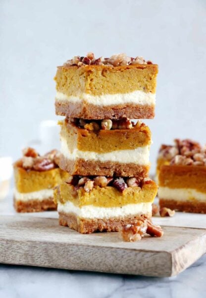 These amazing pumpkin cheesecake bars with candied pecans are delicious and so EASY to make! Full of fall spices, the 4 layers come easily together in a sumptuous dessert that is sure to impress at any holiday gathering.