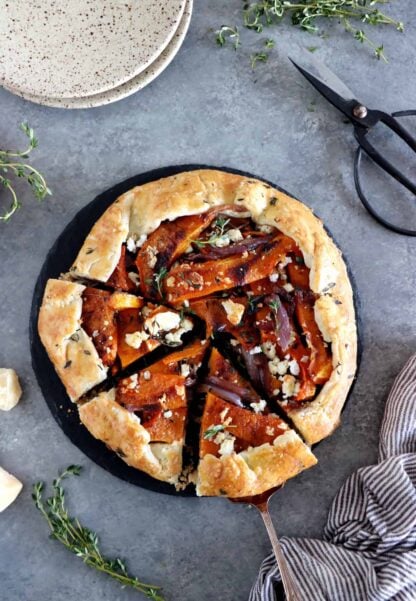 Dans cette galette de courge butternut au parmesan, on y retrouve des oignons caramélisés, de la feta, des tranches de courge butternut rôties au four avec du thym, recouverts d'une pâte à tarte au parmesan croustillante à souhait.