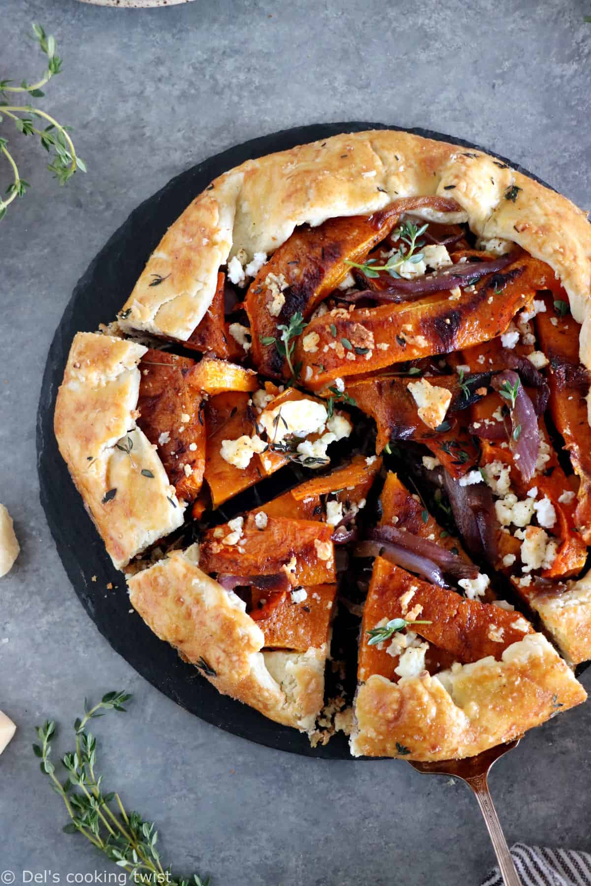 Dans cette galette de courge butternut au parmesan, on y retrouve des oignons caramélisés, de la feta, des tranches de courge butternut rôties au four avec du thym, recouverts d'une pâte à tarte au parmesan croustillante à souhait.