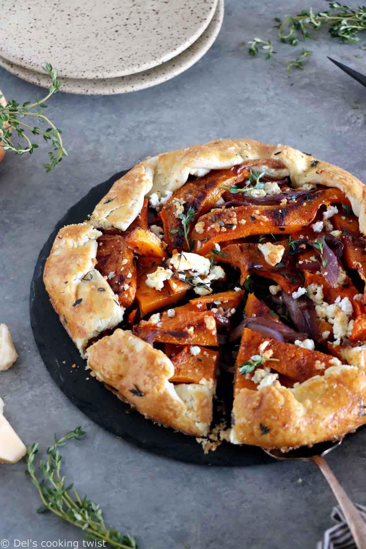 Dans cette galette de courge butternut au parmesan, on y retrouve des oignons caramélisés, de la feta, des tranches de courge butternut rôties au four avec du thym, recouverts d'une pâte à tarte au parmesan croustillante à souhait.