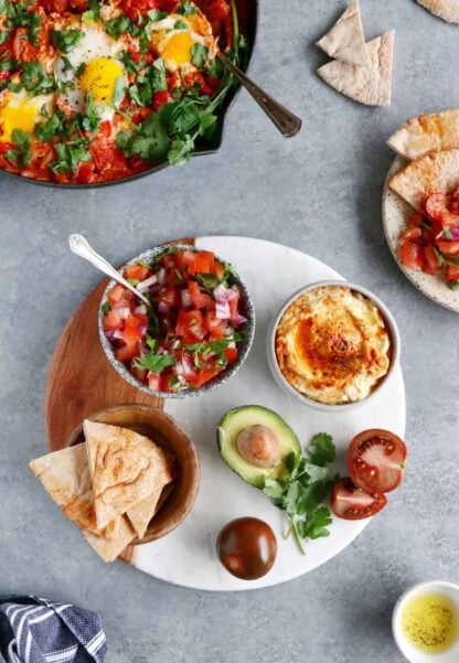 Comment servir une shakshuka ? Placez-la au centre de la table et accompagnez-la d'une déclinaison de petits plats, pains et salade pour faire du repas un véritable festin !