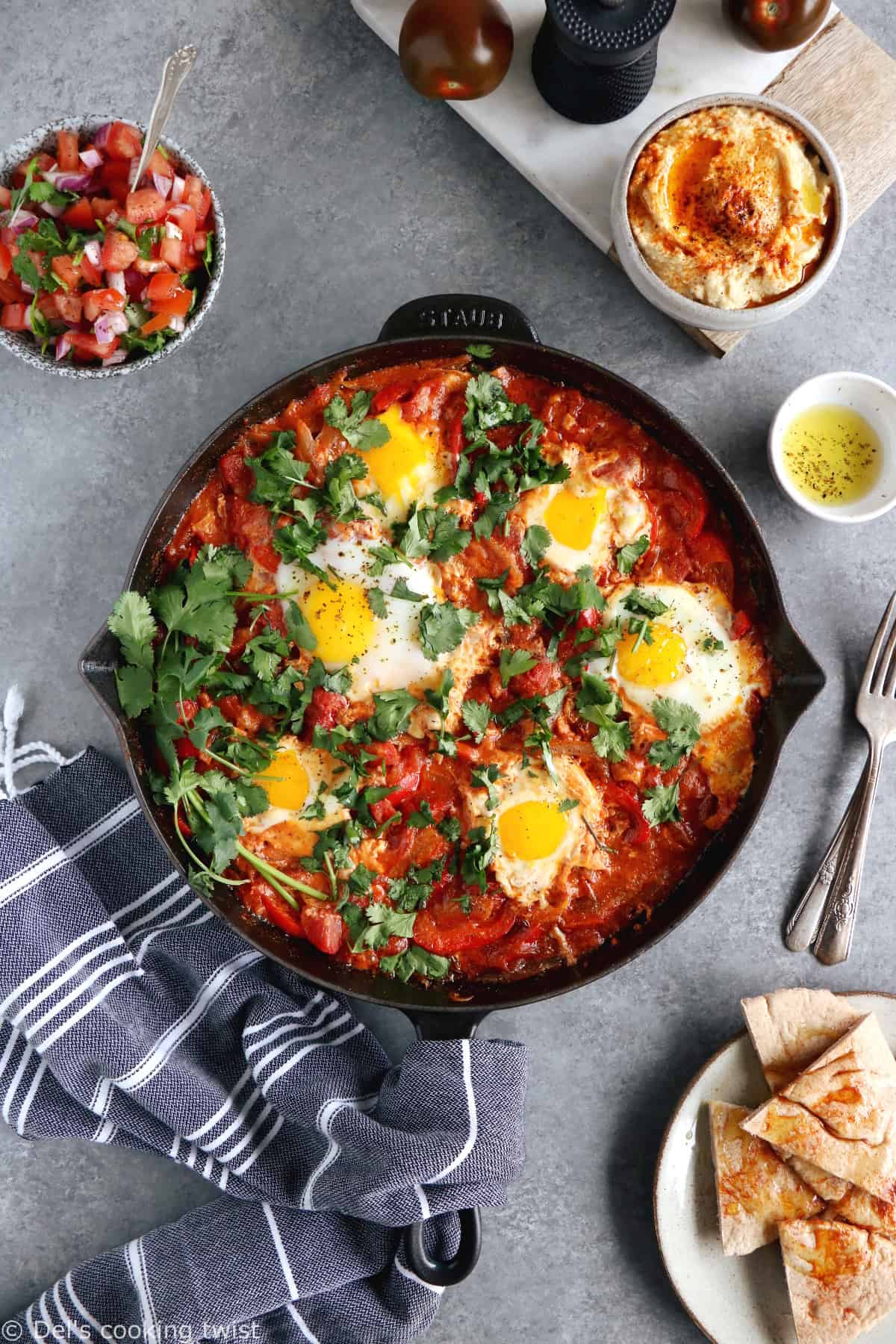 Shakshuka with Feta Cheese is a simple dish consisting of poached eggs in a simmering tomato sauce with feta and spices, traditionally served in a cast iron skillet.