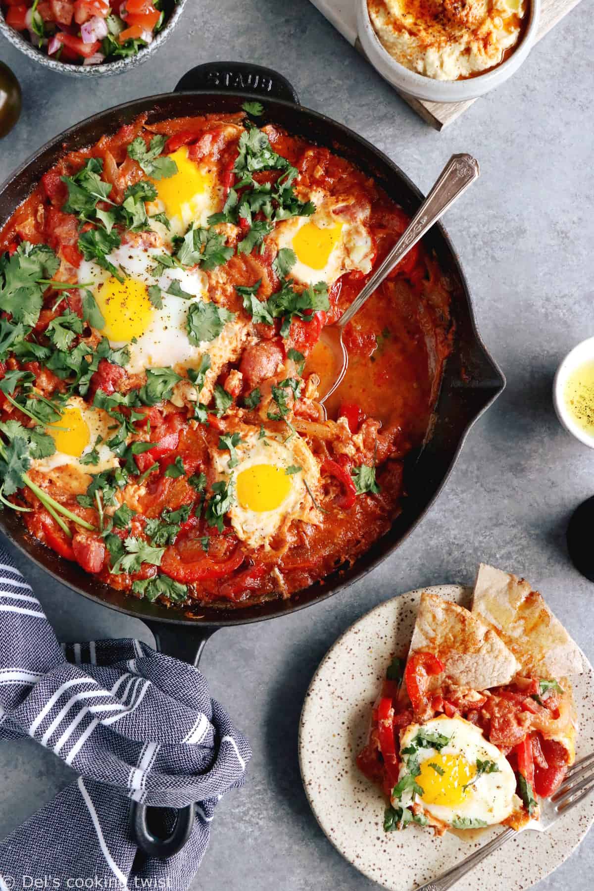 Shakshuka with Feta Cheese is a simple dish consisting of poached eggs in a simmering tomato sauce with feta and spices, traditionally served in a cast iron skillet.