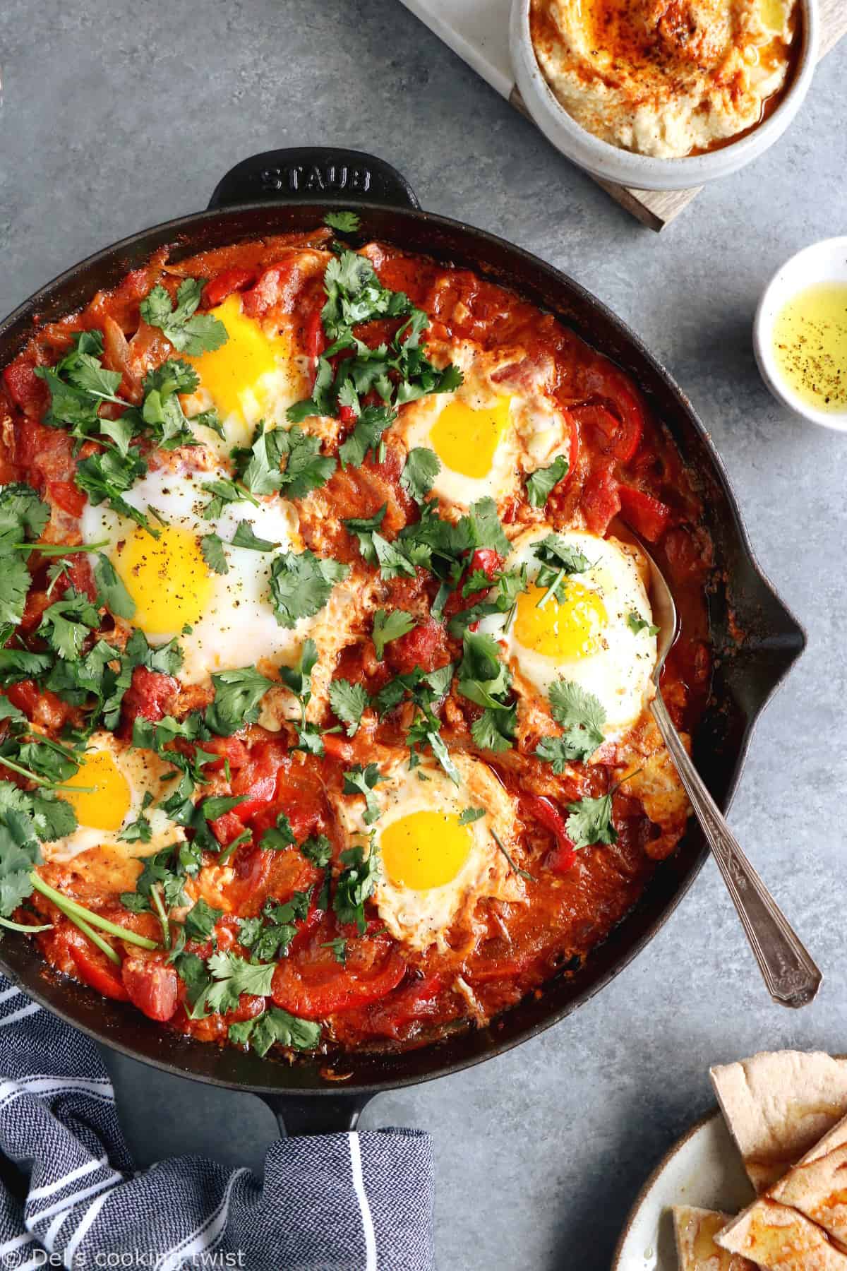 Shakshuka with Feta Cheese is a simple dish consisting of poached eggs in a simmering tomato sauce with feta and spices, traditionally served in a cast iron skillet.