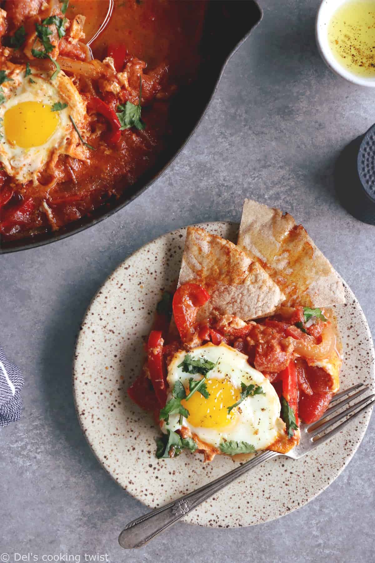 Shakshuka with Feta Cheese is a simple dish consisting of poached eggs in a simmering tomato sauce with feta and spices, traditionally served in a cast iron skillet.