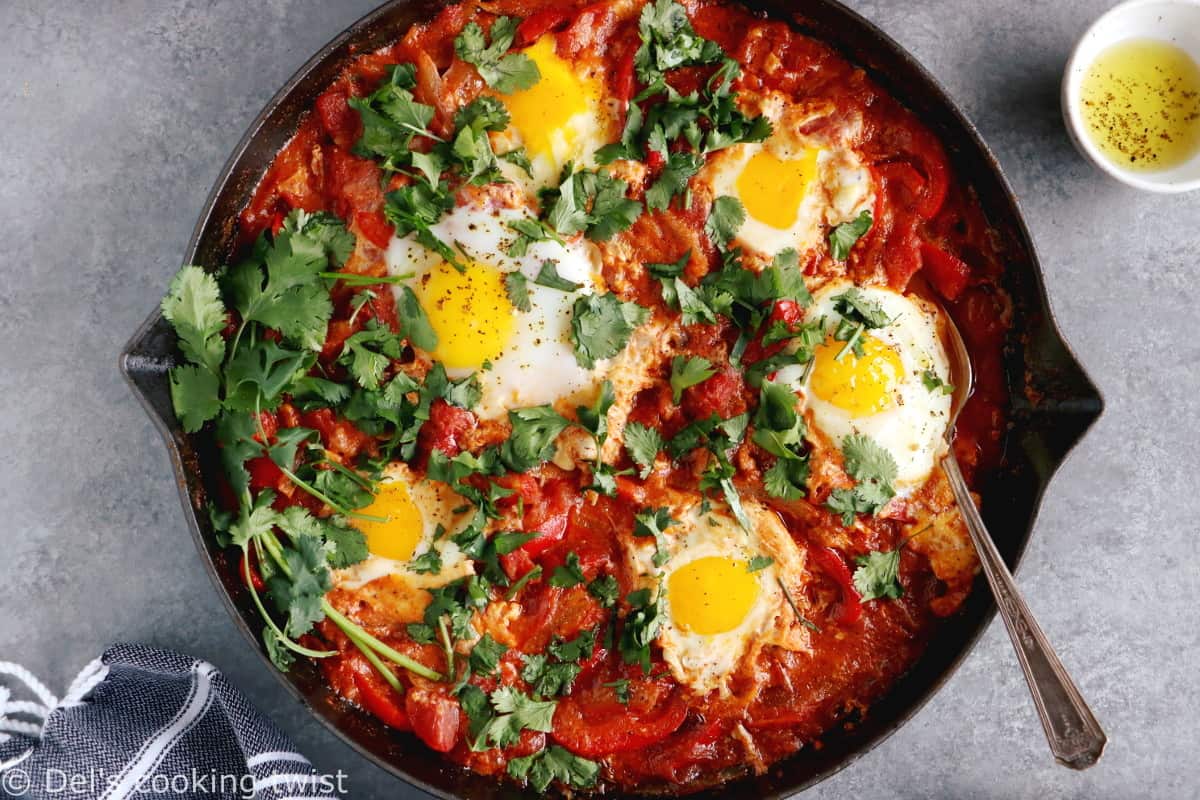 Shakshuka with Feta Cheese is a simple dish consisting of poached eggs in a simmering tomato sauce with feta and spices, traditionally served in a cast iron skillet.