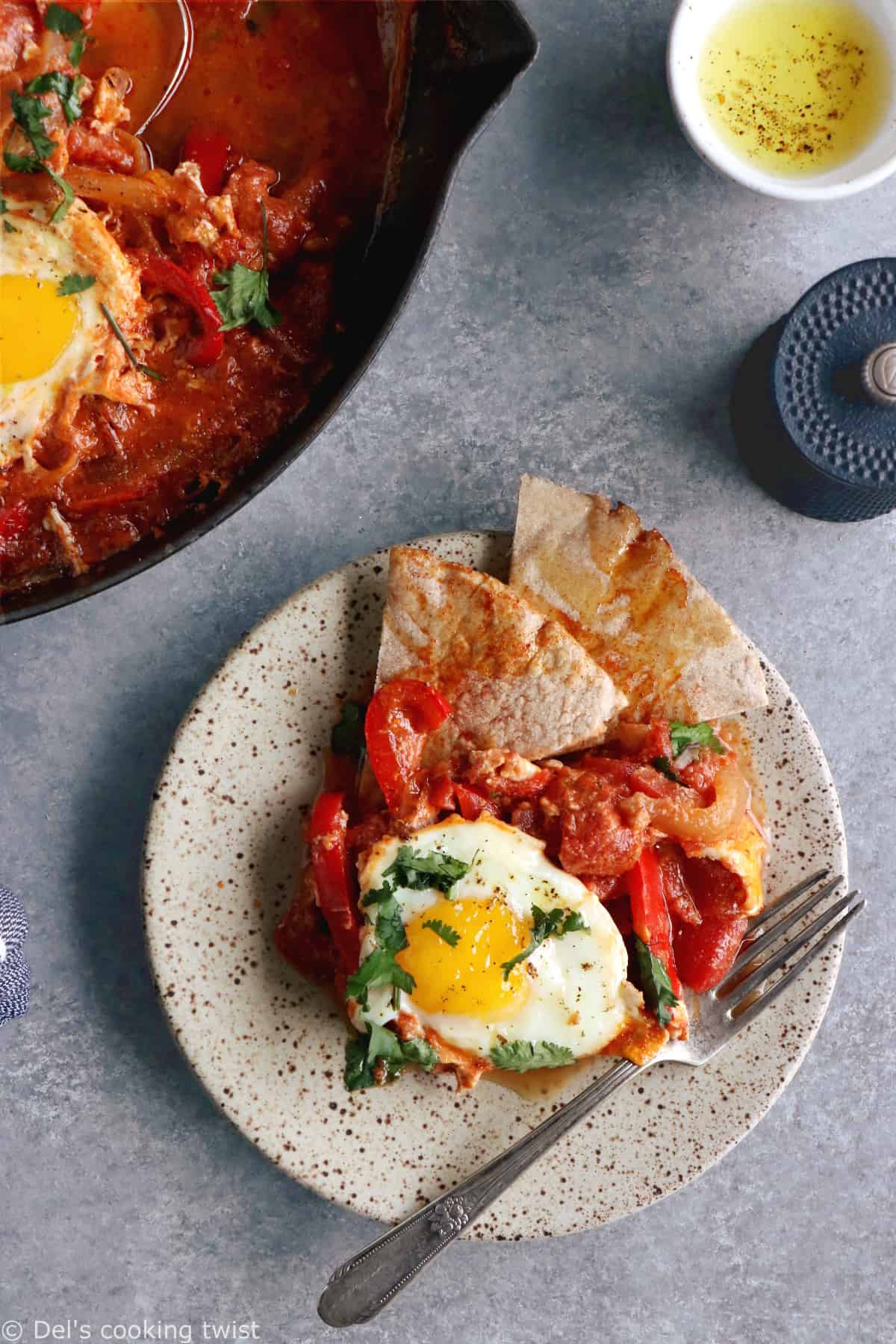 Shakshuka with Feta Cheese is a simple dish consisting of poached eggs in a simmering tomato sauce with feta and spices, traditionally served in a cast iron skillet.