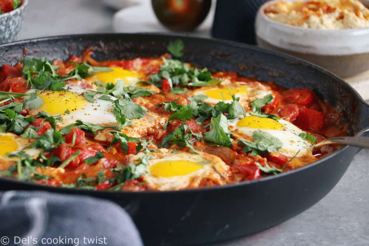 Shakshuka with Feta Cheese is a simple dish consisting of poached eggs in a simmering tomato sauce with feta and spices, traditionally served in a cast iron skillet.