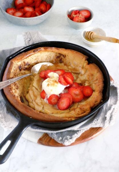 EASY brown butter Dutch Baby pancake with strawberries. It all happens in one pan, it's convivial and packed with delicious flavors of brown butter and cinnamon.