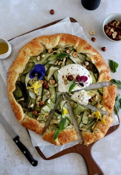 This beautiful zucchini galette is prepared with honey zucchini ribbons, toasted hazelnuts, and some burrata cheese bursting with refreshing flavors.