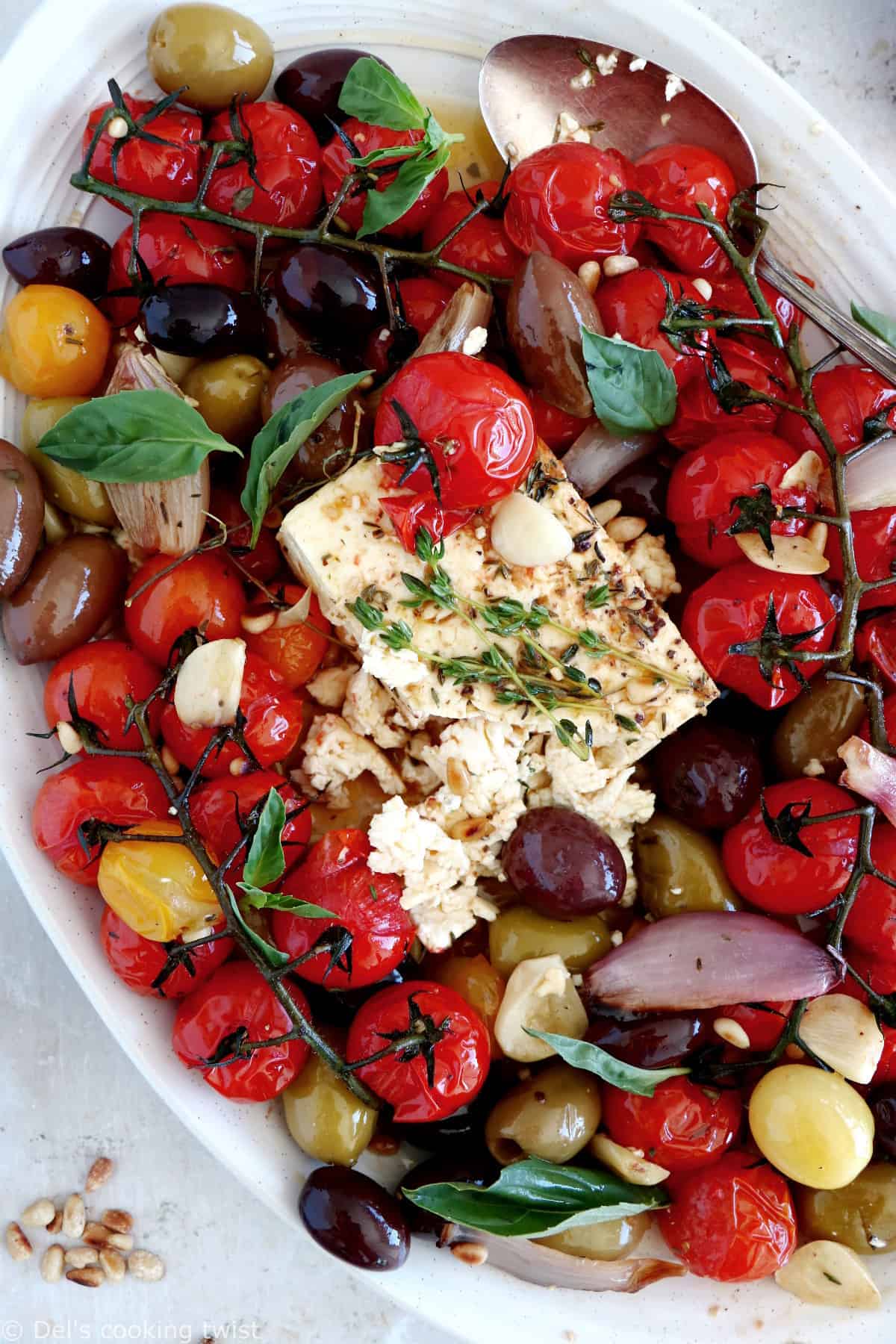 Découvrez ce plat de "baked feta", qui consiste en de la feta rôtie au four avec des tomates cerises confites et des olives marinées dans un mélange d'huile d'olive et d'herbes.