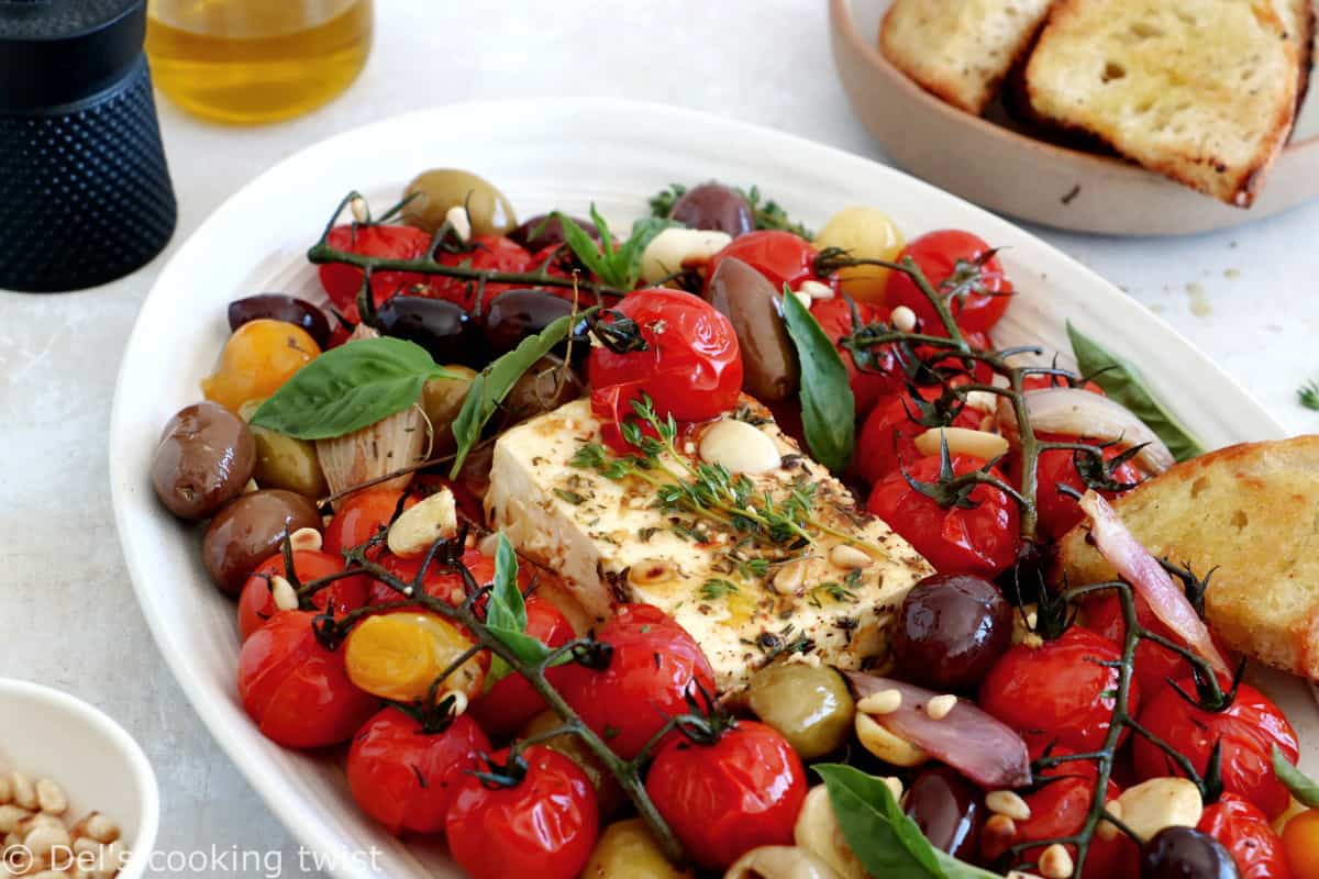 Découvrez ce plat de "baked feta", qui consiste en de la feta rôtie au four avec des tomates cerises confites et des olives marinées dans un mélange d'huile d'olive et d'herbes.