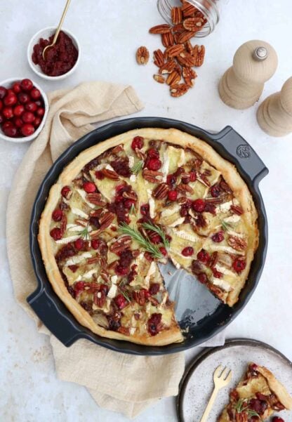 Cette tarte fine au Brie et aux cranberries, réalisée sur une base de pâte feuilletée, constitue une entrée élégante pour les fêtes de fin d'année.