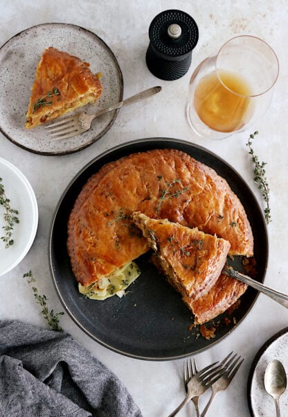 Cette tourte aux pommes de terre est née de l'idée d'une galette des rois salée. On y retrouve des fines lamelles de pommes de terre, du poireau et du Comté entre deux disques de pâte feuilletée.