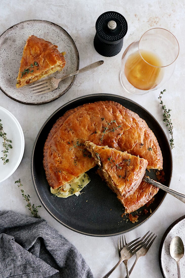 Cette tourte aux pommes de terre est née de l'idée d'une galette des rois salée. On y retrouve des fines lamelles de pommes de terre, du poireau et du Comté entre deux disques de pâte feuilletée.