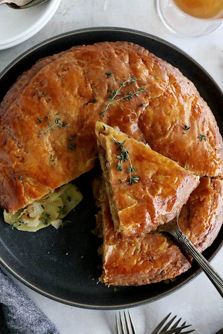 Cette tourte aux pommes de terre est née de l'idée d'une galette des rois salée. On y retrouve des fines lamelles de pommes de terre, du poireau et du Comté entre deux disques de pâte feuilletée.