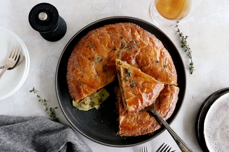 Cette tourte aux pommes de terre est née de l'idée d'une galette des rois salée. On y retrouve des fines lamelles de pommes de terre, du poireau et du Comté entre deux disques de pâte feuilletée.