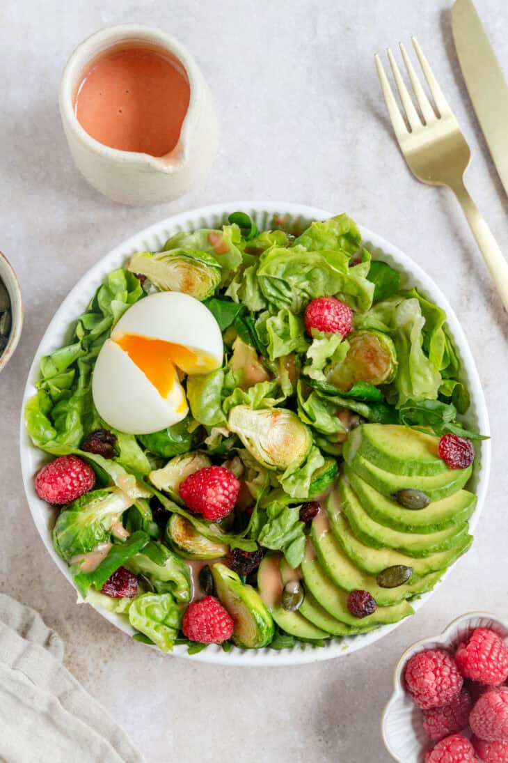 Simple et délicieuse salade d'avocat, framboises et oeufs mollets avec une vinaigrette de framboises.