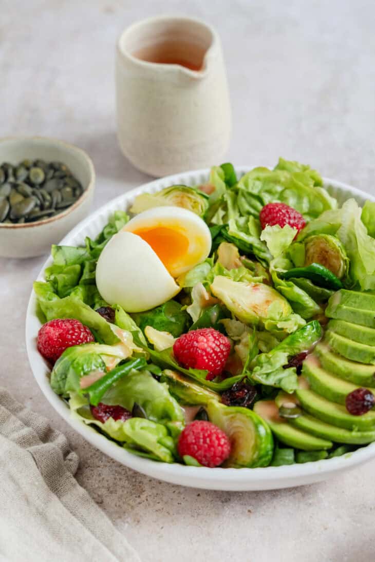 Simple et délicieuse salade d'avocat, framboises et oeufs mollets avec une vinaigrette de framboises.