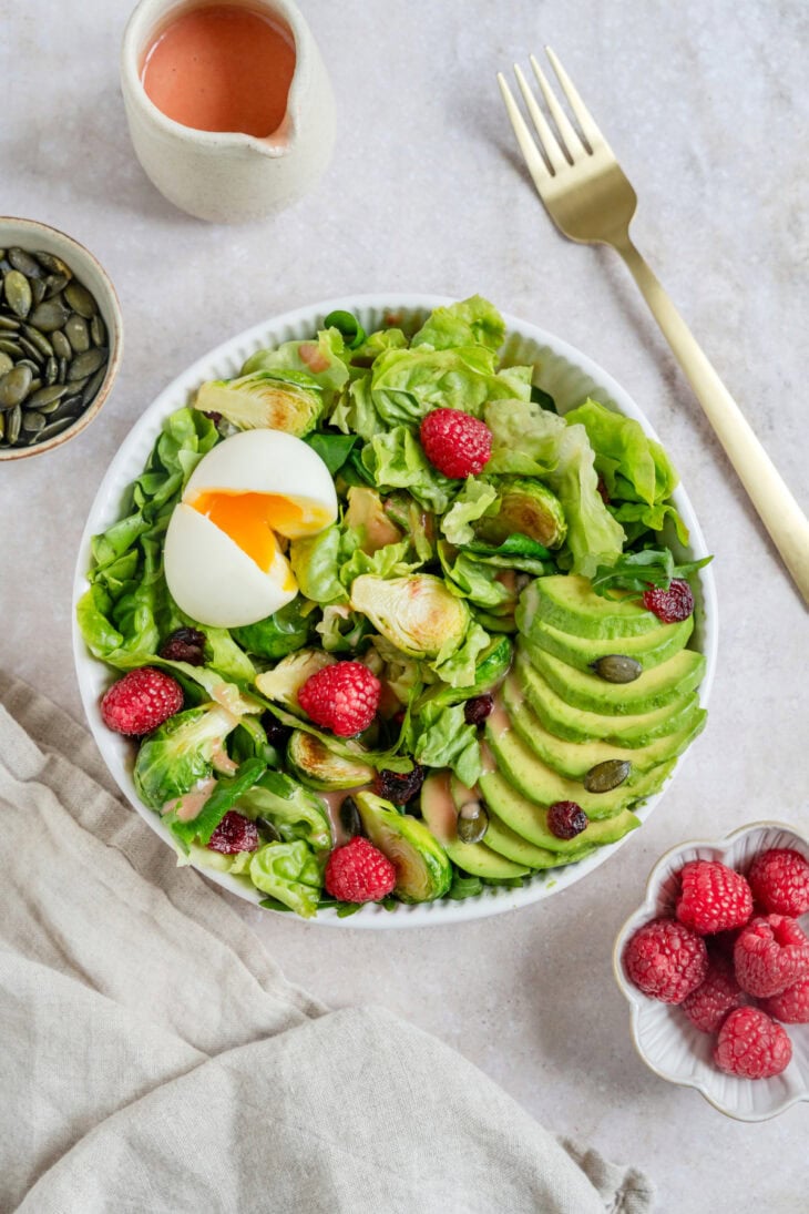 Simple et délicieuse salade d'avocat, framboises et oeufs mollets avec une vinaigrette de framboises.