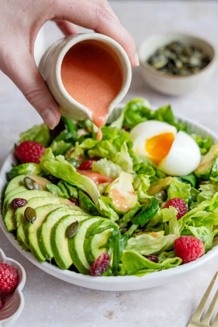 Simple et délicieuse salade d'avocat, framboises et oeufs mollets avec une vinaigrette de framboises.