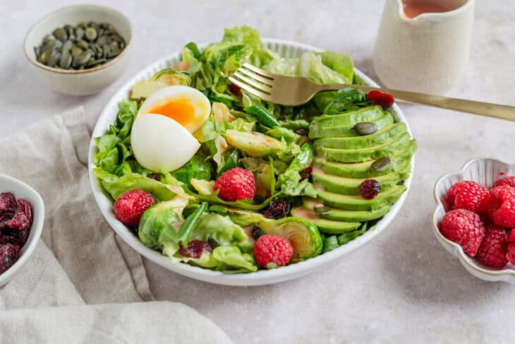 Simple et délicieuse salade d'avocat, framboises et oeufs mollets avec une vinaigrette de framboises.