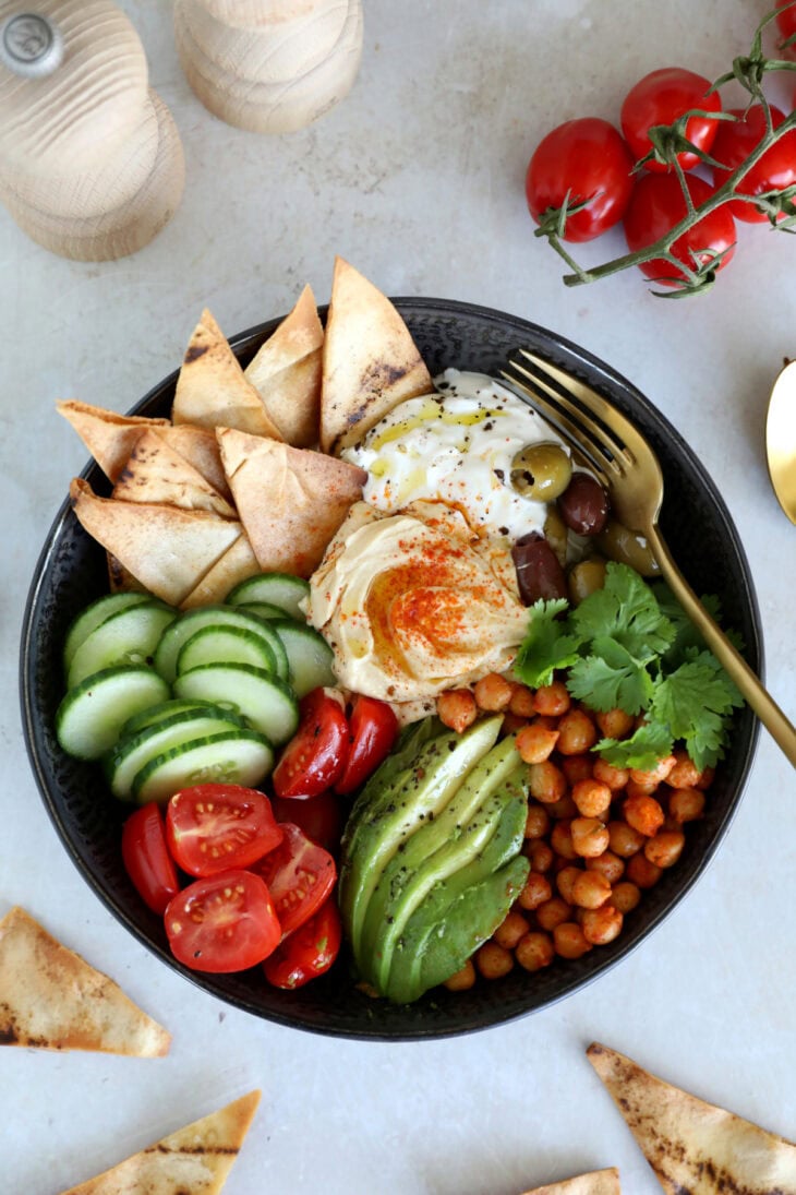This Mediterranean mezze bowl combines a variety of hummus, tzatziki, roasted chickpeas, fresh and pickled veggies, served with pita bread.